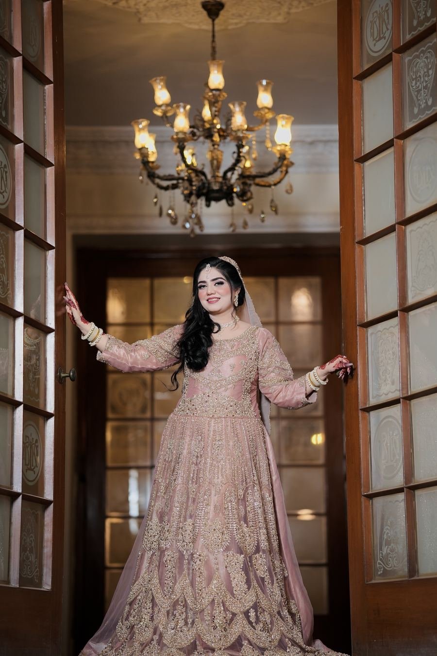 Bride in a blush gown under a crystal chandelier