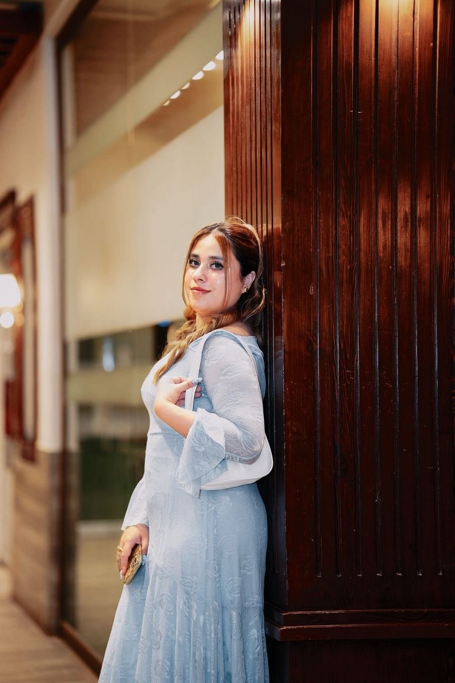 Bridal portrait in a pale blue dress beside a wooden door